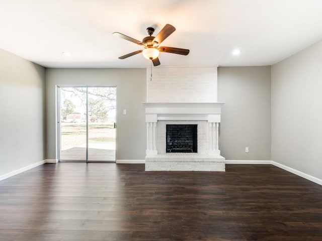 unfurnished living room with a fireplace, ceiling fan, and dark wood-type flooring