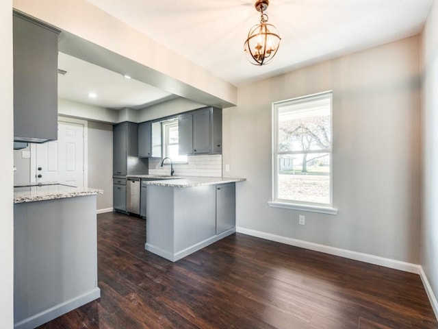 kitchen featuring dishwasher, an inviting chandelier, dark hardwood / wood-style floors, decorative light fixtures, and kitchen peninsula