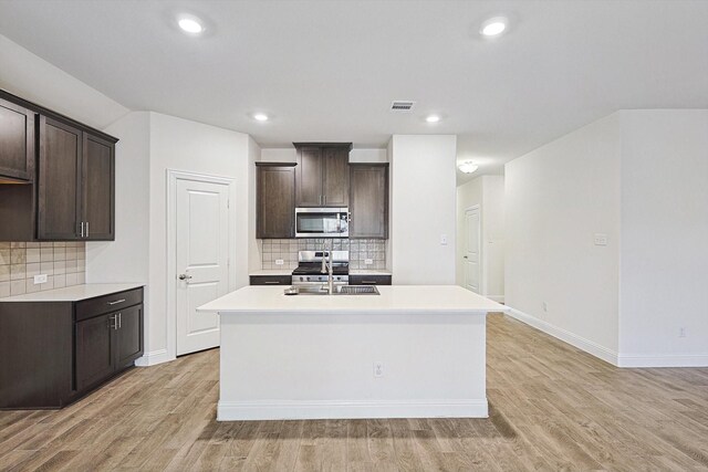 kitchen featuring a center island with sink, appliances with stainless steel finishes, and tasteful backsplash