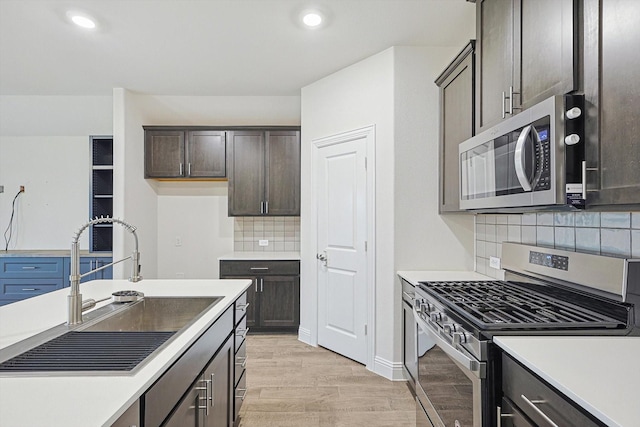 kitchen with dark brown cabinetry, sink, tasteful backsplash, light hardwood / wood-style floors, and appliances with stainless steel finishes