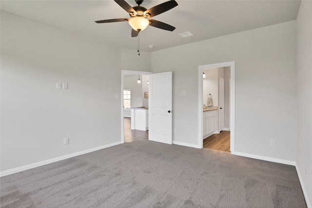 unfurnished bedroom with ensuite bathroom, ceiling fan, and light colored carpet