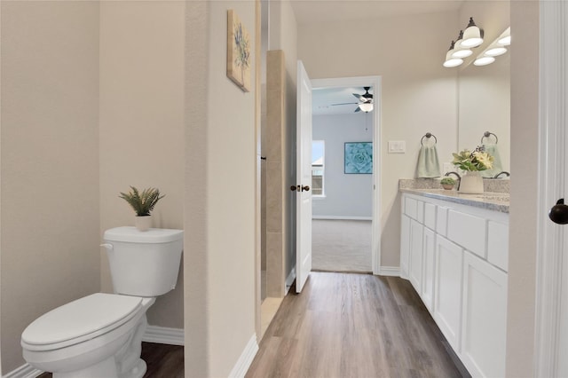 bathroom featuring ceiling fan, toilet, vanity, and hardwood / wood-style flooring