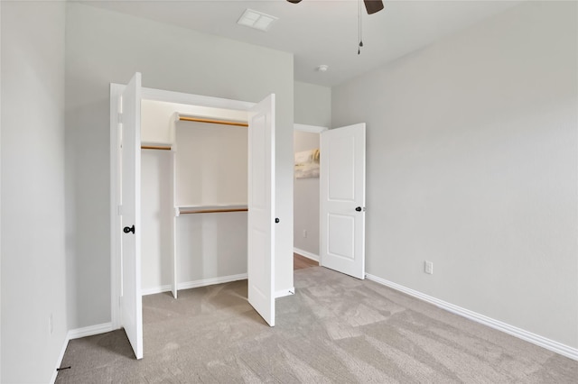 unfurnished bedroom featuring a closet, light colored carpet, and ceiling fan