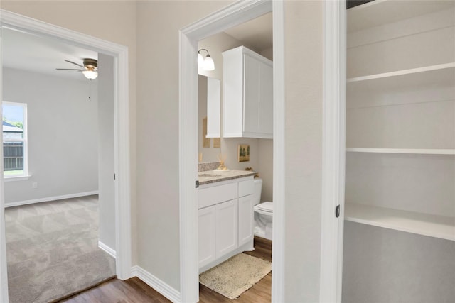 bathroom with ceiling fan, hardwood / wood-style floors, vanity, and toilet