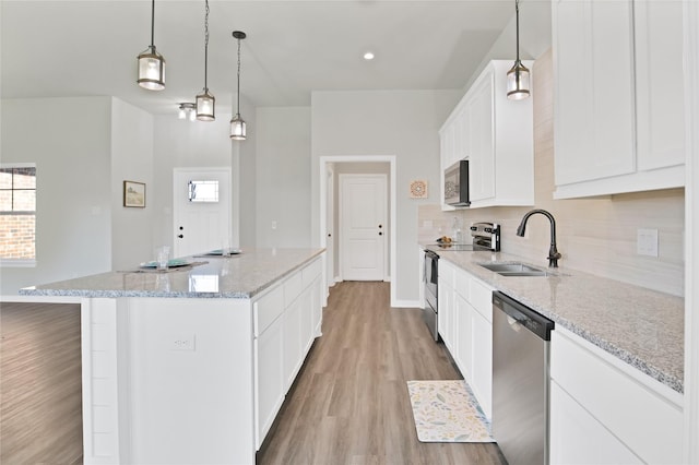 kitchen with a center island, white cabinets, sink, appliances with stainless steel finishes, and decorative light fixtures