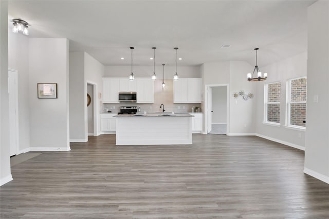 kitchen with hanging light fixtures, stainless steel appliances, wood-type flooring, a kitchen island with sink, and white cabinets