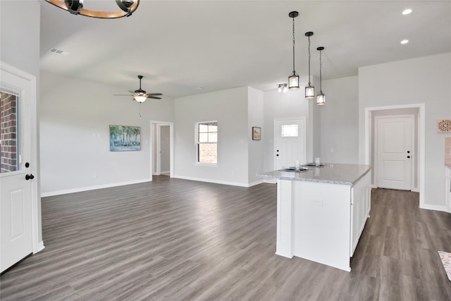 kitchen with ceiling fan, light stone counters, dark hardwood / wood-style floors, decorative light fixtures, and white cabinets