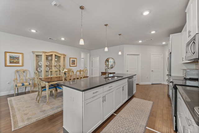 kitchen featuring white cabinets, stainless steel appliances, a kitchen island with sink, and sink