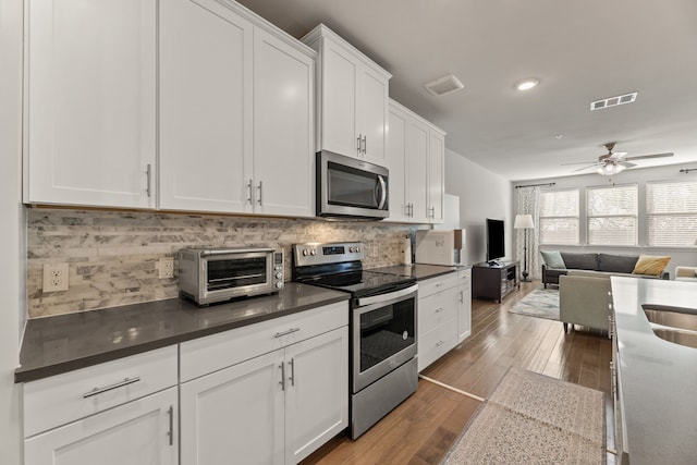 kitchen featuring backsplash, hardwood / wood-style flooring, ceiling fan, white cabinetry, and stainless steel appliances