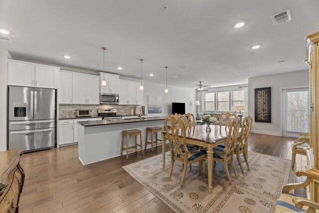 dining space featuring hardwood / wood-style flooring, ceiling fan, and sink