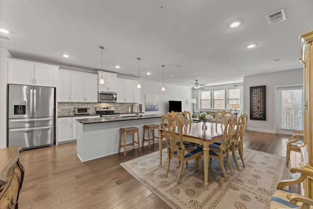 dining room with sink, hardwood / wood-style floors, and ceiling fan