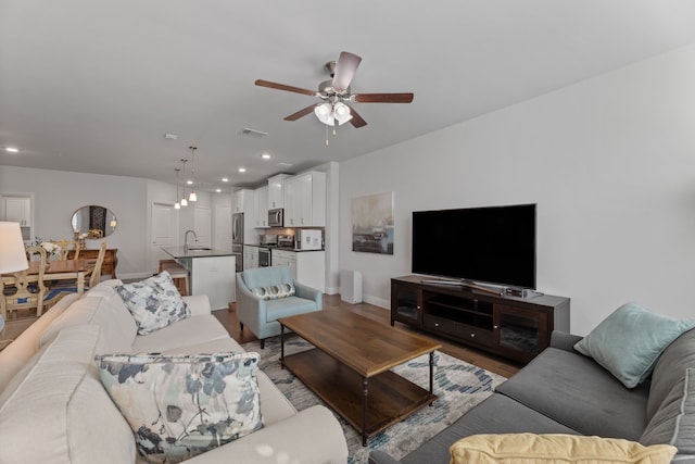 living room with ceiling fan, sink, and wood-type flooring