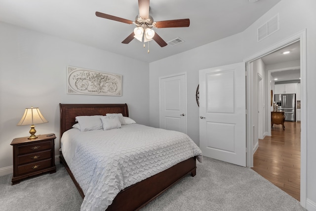 bedroom featuring hardwood / wood-style floors, ceiling fan, stainless steel fridge with ice dispenser, and a closet