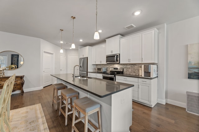 kitchen featuring a breakfast bar area, dark wood-type flooring, a center island with sink, and stainless steel appliances