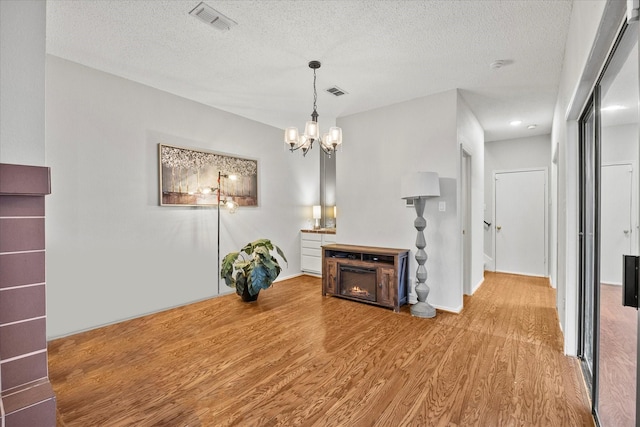 living room featuring a chandelier, light hardwood / wood-style floors, and a textured ceiling