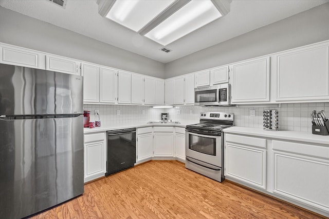 kitchen with sink, backsplash, stainless steel appliances, light hardwood / wood-style floors, and white cabinets