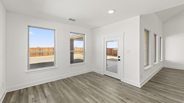 unfurnished room featuring wood finished floors, visible vents, and baseboards