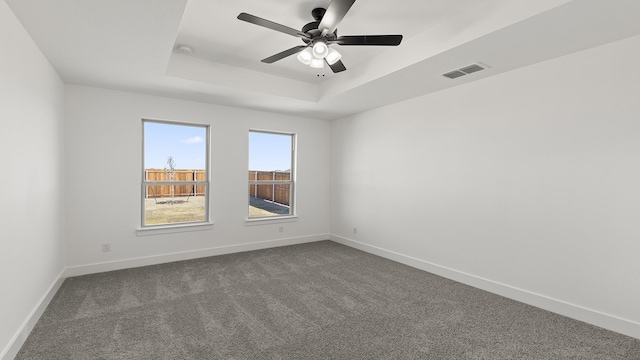 spare room featuring baseboards, visible vents, and a raised ceiling