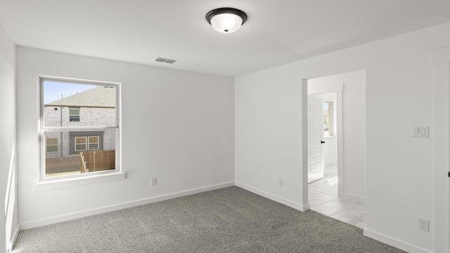 unfurnished room with baseboards, visible vents, and light colored carpet