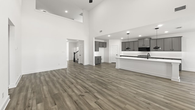 unfurnished living room with dark wood-style flooring, recessed lighting, visible vents, stairway, and baseboards