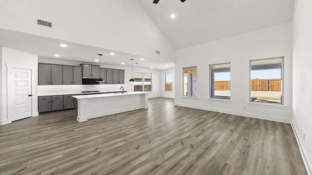 kitchen with decorative light fixtures, a center island with sink, gray cabinets, light countertops, and open floor plan