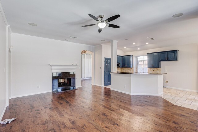 unfurnished living room featuring ornamental molding, ceiling fan, dark wood-type flooring, and a premium fireplace