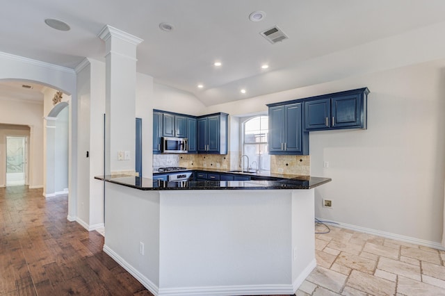 kitchen with stainless steel appliances, blue cabinets, dark stone countertops, crown molding, and light wood-type flooring