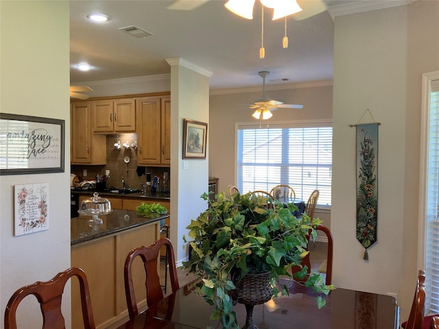 kitchen with backsplash, ceiling fan, ornamental molding, and dark stone countertops