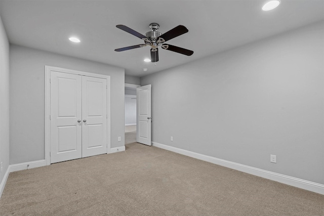 unfurnished bedroom with ceiling fan, light colored carpet, and a closet