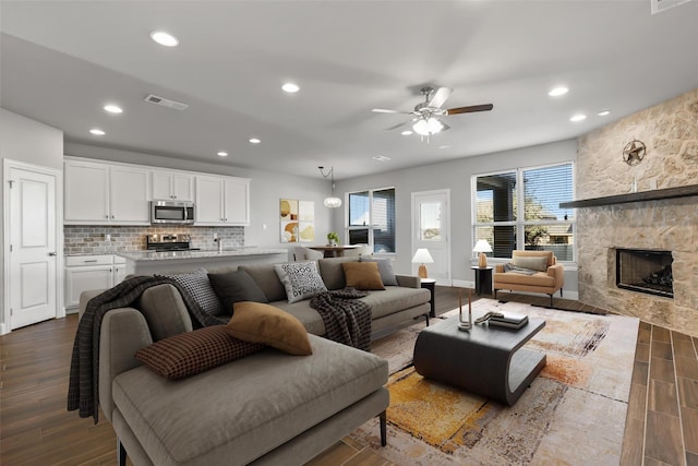 living room with ceiling fan, dark hardwood / wood-style flooring, and a fireplace