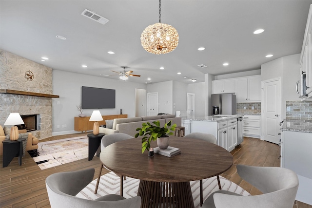 dining room with a fireplace and ceiling fan with notable chandelier