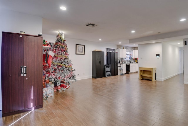 interior space featuring stainless steel fridge, white cabinets, and light wood-type flooring