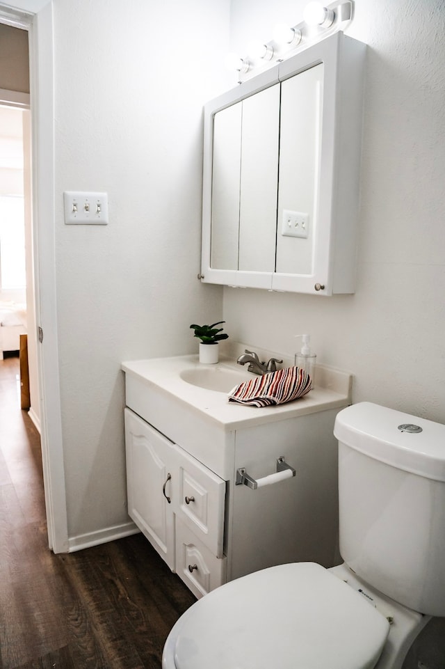 bathroom featuring toilet, vanity, and hardwood / wood-style flooring