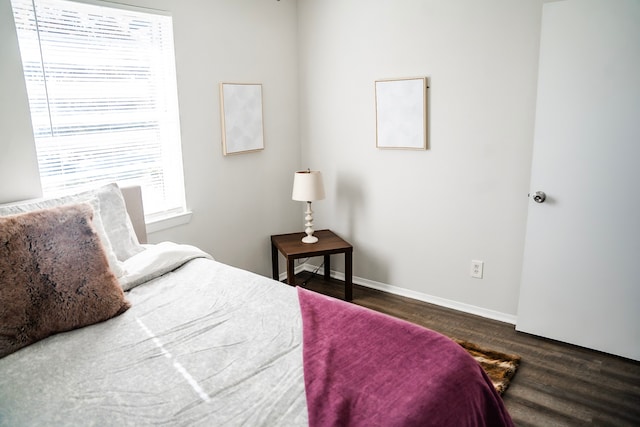 bedroom with dark hardwood / wood-style floors and multiple windows