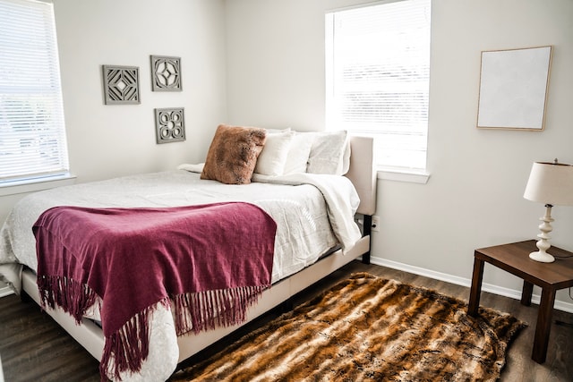 bedroom with multiple windows and dark hardwood / wood-style floors