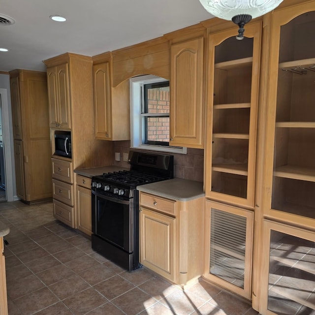 kitchen featuring backsplash, light brown cabinetry, dark tile patterned floors, and black gas range oven