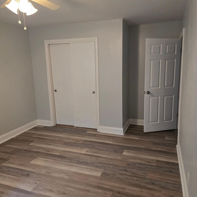 unfurnished bedroom featuring ceiling fan, a closet, and dark wood-type flooring