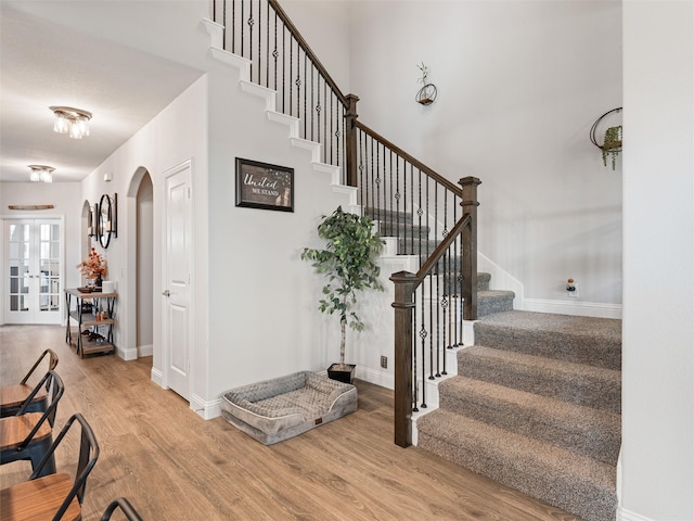 stairs with french doors and wood-type flooring