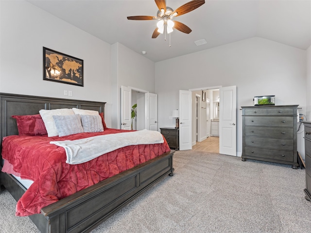 bedroom featuring ensuite bath, light colored carpet, vaulted ceiling, and ceiling fan