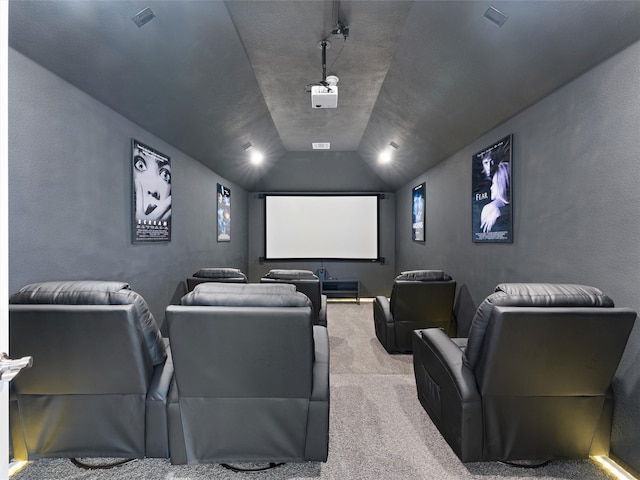 home theater room featuring a textured ceiling, light colored carpet, and vaulted ceiling