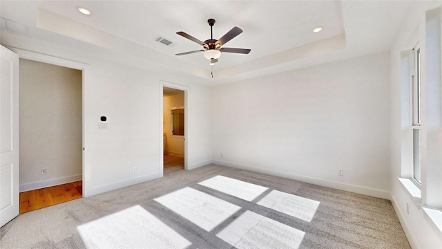 carpeted bedroom featuring connected bathroom, a raised ceiling, and ceiling fan