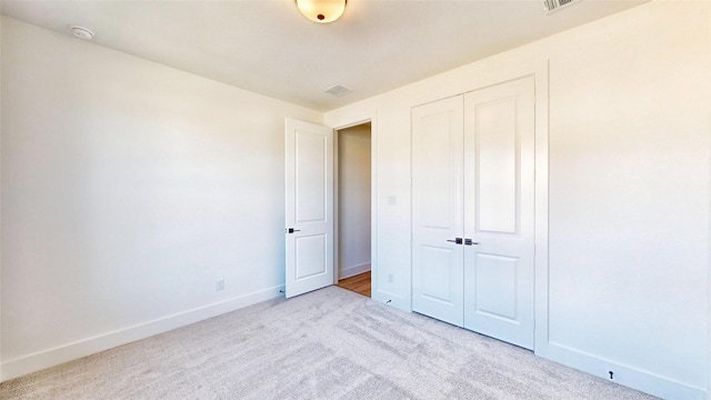 unfurnished bedroom with light carpet and a closet