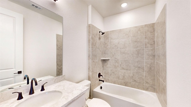 full bathroom with vanity, tiled shower / bath combo, and toilet