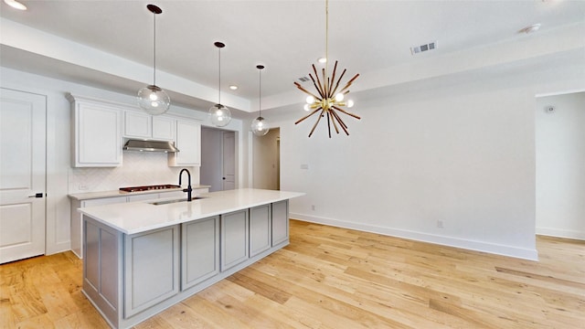 kitchen featuring a kitchen island with sink, sink, and light wood-type flooring