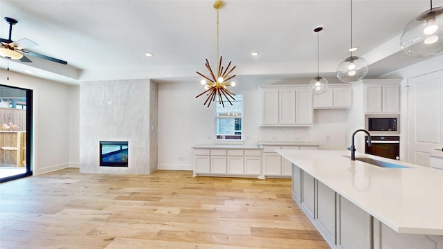 kitchen featuring white cabinetry, a large island with sink, built in microwave, and sink