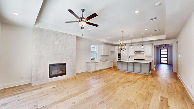 kitchen with a kitchen island with sink, pendant lighting, a healthy amount of sunlight, and light hardwood / wood-style flooring