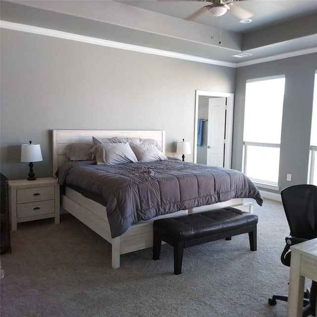 carpeted bedroom featuring ceiling fan, ornamental molding, and a tray ceiling