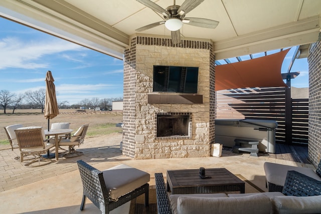 view of patio / terrace with an outdoor living space with a fireplace and ceiling fan