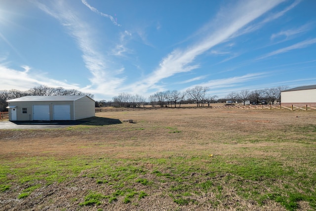 view of yard featuring an outbuilding, a rural view, and a garage