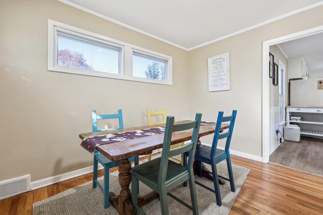 dining space with light hardwood / wood-style floors and ornamental molding